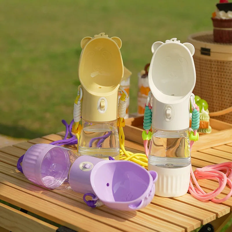 Set of colorful pet water bottles with bear-shaped lids on a wooden surface.